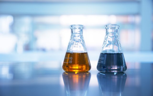 two glass flasks with orange and black solution in chemical science laboratory background